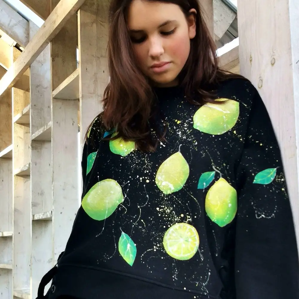 Девушка демонстрирует готовый свитшот с авторской росписью.